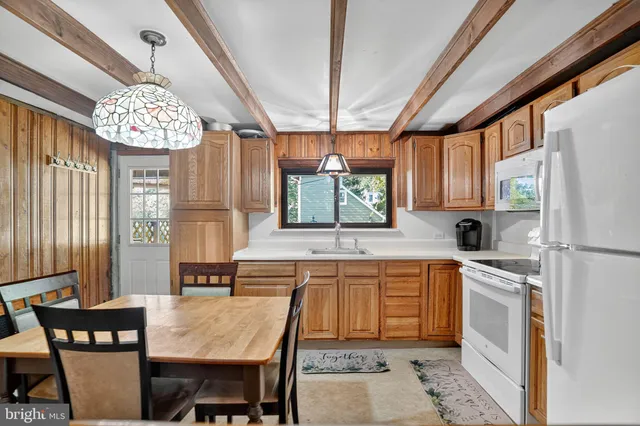 a kitchen with stainless steel appliances granite countertop a sink dishwasher a stove a refrigerator a dining table and chairs with wooden floor