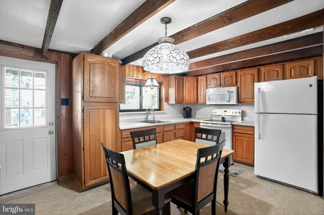 a kitchen with stainless steel appliances granite countertop a refrigerator a sink dishwasher a dining table and chairs with wooden floor