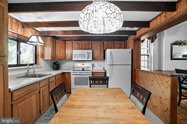 a open kitchen with stainless steel appliances granite countertop a refrigerator a sink dishwasher a stove and a dining table with wooden floor