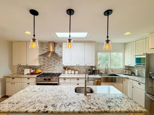 a kitchen with stainless steel appliances kitchen island granite countertop a sink a counter top space and living room view