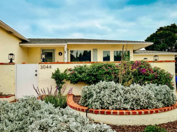 a front view of a house with a yard and potted plants