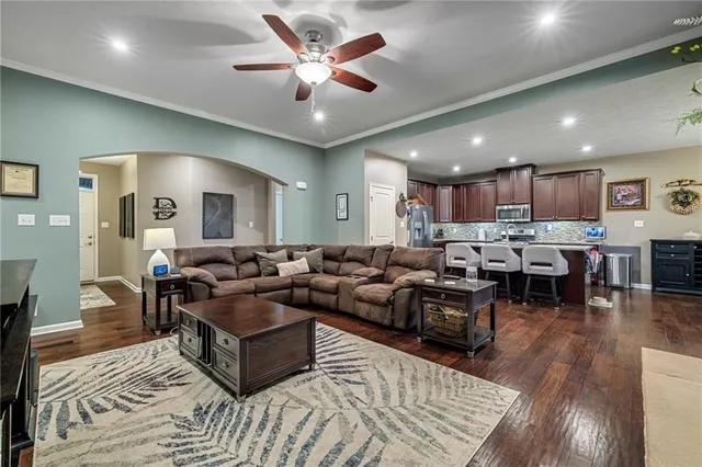 a living room with furniture kitchen view and a wooden floor