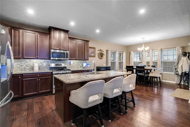 a large kitchen with cabinets chairs and wooden floor