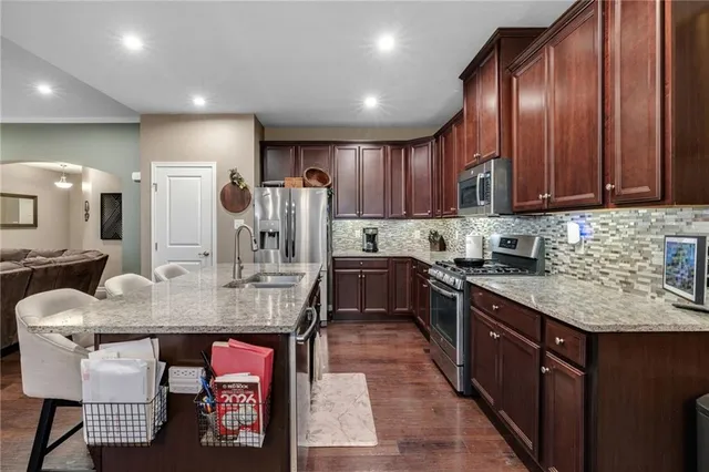 a kitchen with stainless steel appliances granite countertop a kitchen island hardwood floor sink and stove