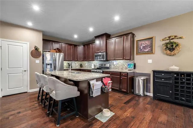 a kitchen with kitchen island granite countertop wooden floors and wooden cabinets
