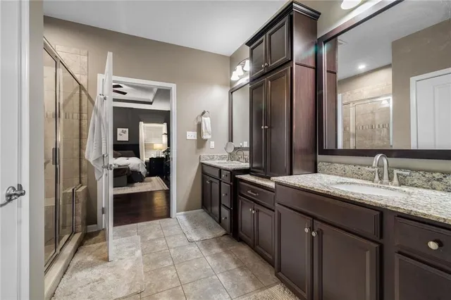 a spacious bathroom with a granite countertop sink a mirror and shower