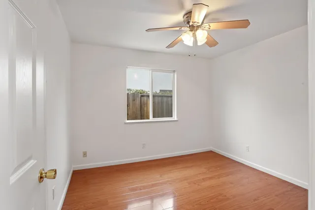 a view of an empty room with window and chandelier fan