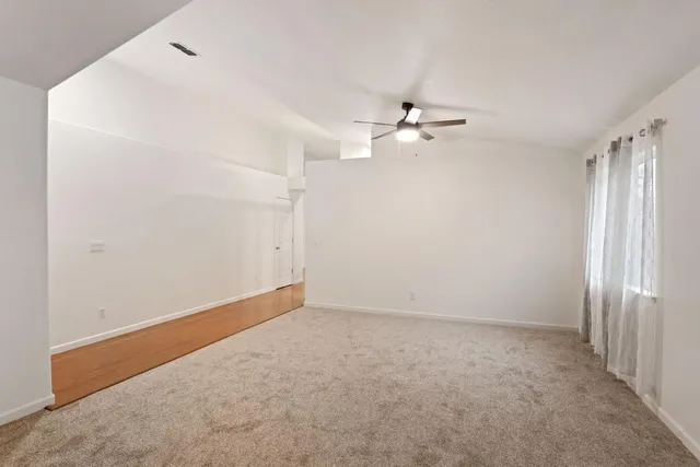 an empty room with a ceiling fan and a window