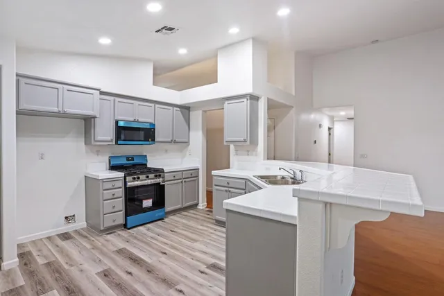 a kitchen with granite countertop a stove a sink and a refrigerator