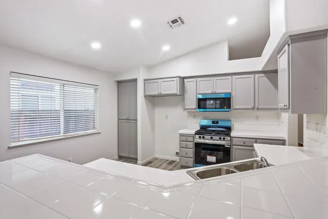 a view of an empty room with wooden floor fireplace and a window