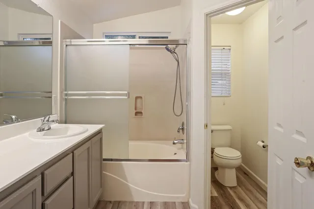 an empty room with wooden floor fan and window