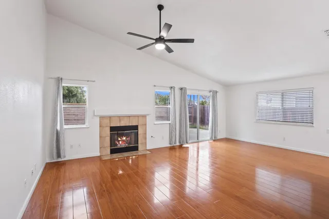 a view of an empty room with wooden floor fireplace and a window