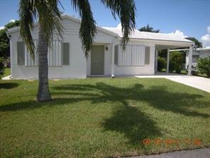 a view of a white house next to a yard with palm trees