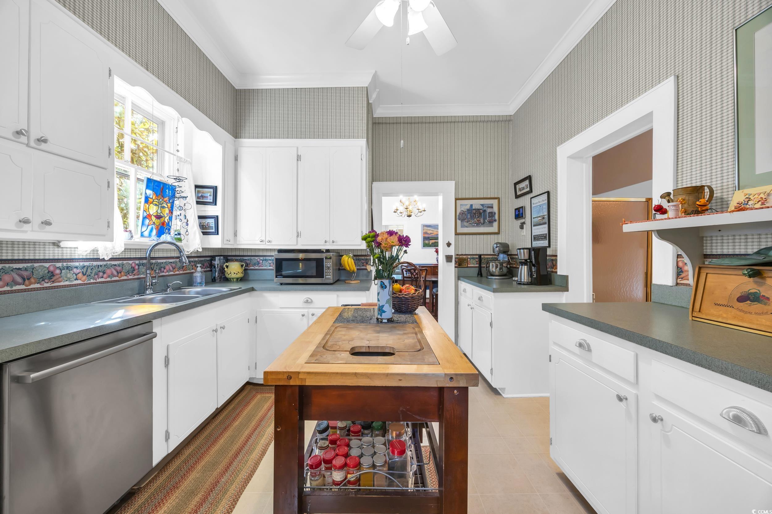 209 Cannon Street Georgetown, SC 29440 - Photo 14 of 34 Kitchen with wallpapered walls, stainless steel appliances, white cabinets, crown molding, and a chandelier
