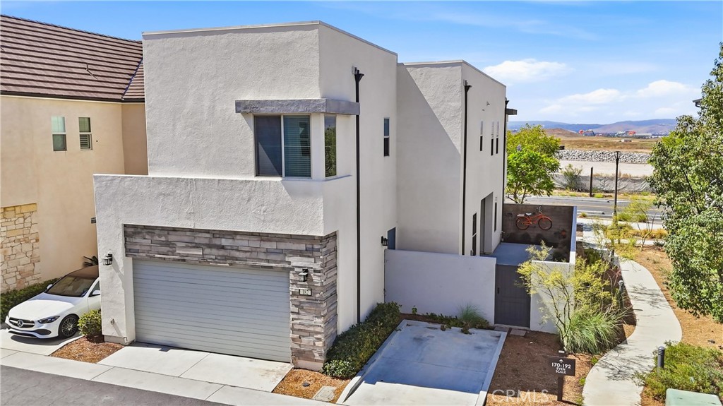 182 Scale Irvine, CA 92618 - Photo 48 of 61 The garage side tells the full story of the home's footprint. Private gate, stone detail, mountain views behind it, and room for everything.