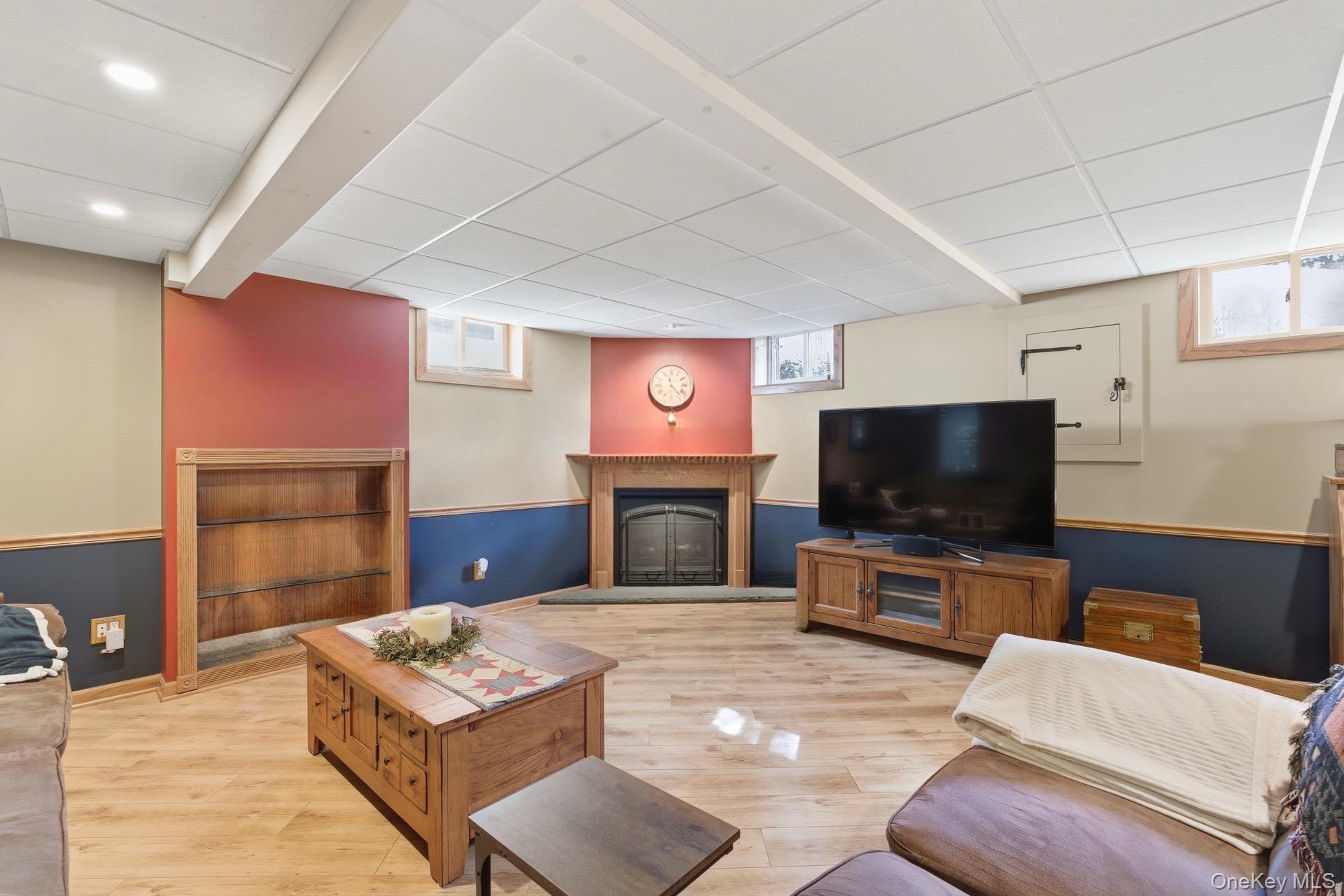 347 Wading River Road Manorville, NY 11949 - Photo 16 of 30 Living area with a fireplace with raised hearth, light wood-style floors, and a drop ceiling