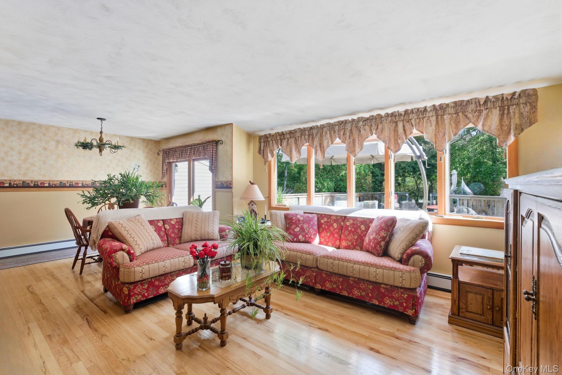 347 Wading River Road Manorville, NY 11949 - Photo 3 of 30 Living area featuring light wood-type flooring, wallpapered walls, a chandelier, and baseboard heating