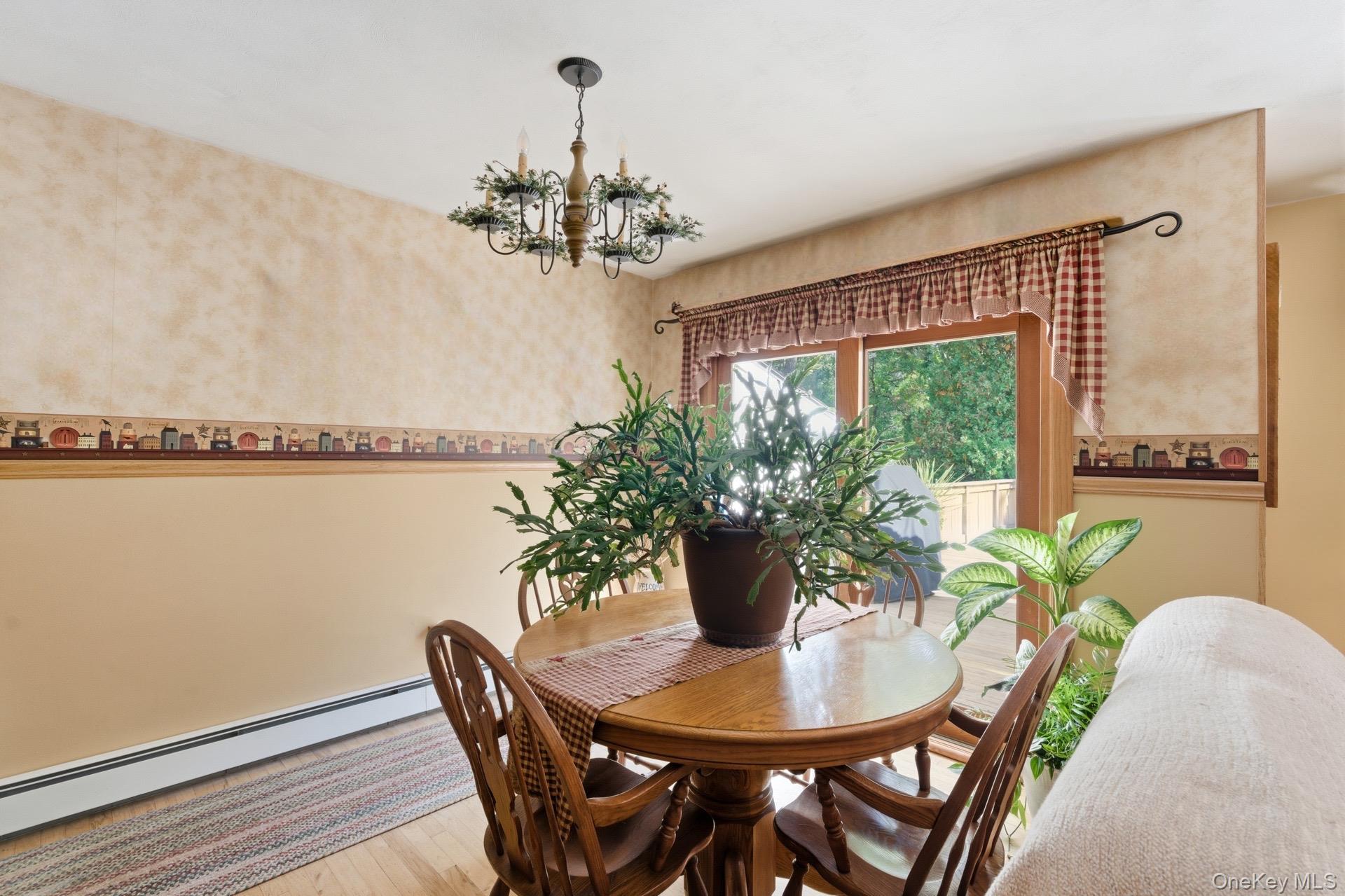 347 Wading River Road Manorville, NY 11949 - Photo 5 of 30 Dining area featuring wood finished floors, a chandelier, and a baseboard heating unit