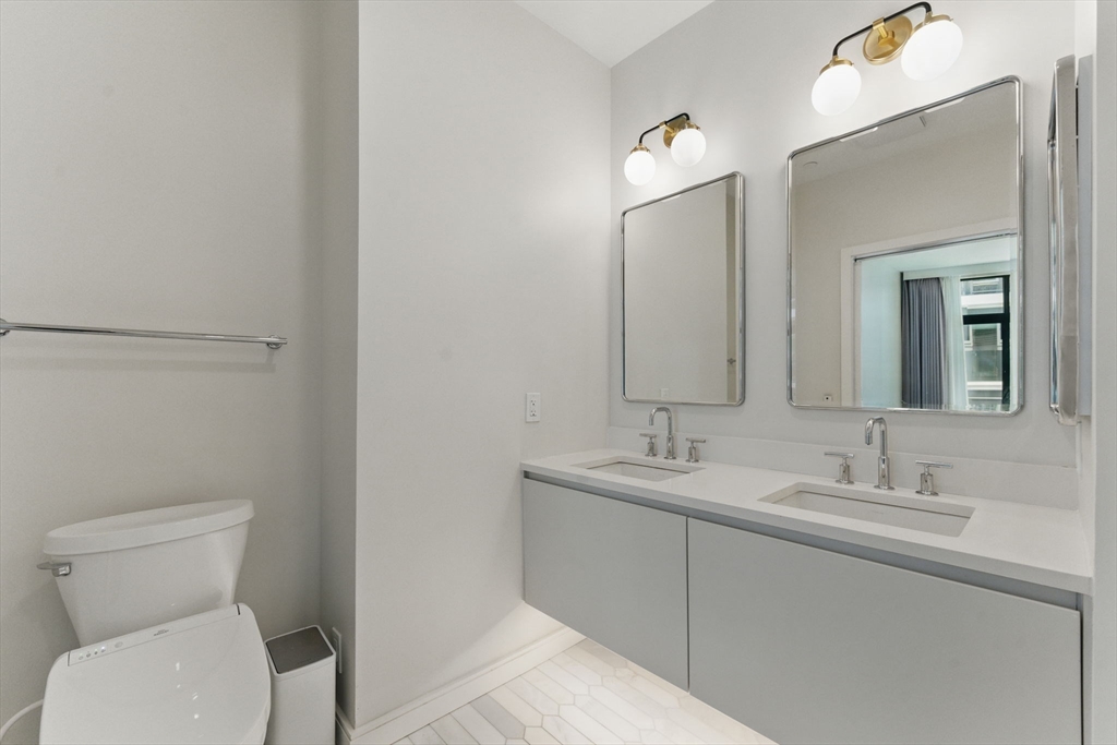 191 Washington Street, Unit 524 Boston, MA 02135 - Photo 19 of 42 a bathroom with a toilet sink and mirror