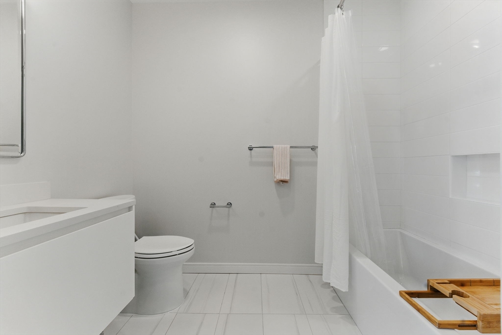 191 Washington Street, Unit 524 Boston, MA 02135 - Photo 24 of 42 a bathroom with a granite countertop toilet and a sink
