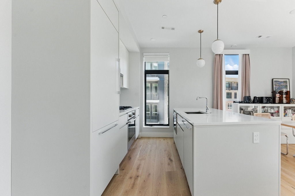 191 Washington Street, Unit 524 Boston, MA 02135 - Photo 9 of 42 a kitchen with kitchen island a sink appliances and cabinets