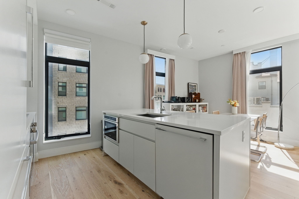 191 Washington Street, Unit 524 Boston, MA 02135 - Photo 10 of 42 a kitchen with kitchen island a sink a stove and a refrigerator with wooden floor