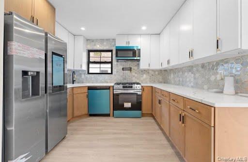 249-17 147th Road, Unit 1 Queens, NY 11422 - Photo 3 of 13 Modern kitchen featuring a stainless steel refrigerator, white upper cabinetry, natural wood-finish lower cabinetry, white countertops, and a patterned tile backsplash