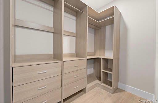 249-17 147th Road, Unit 1 Queens, NY 11422 - Photo 7 of 13 walk in closet system featuring natural wood-finish storage, multiple shelving units, integrated drawers with modern pulls, and corner shelving for optimized organization