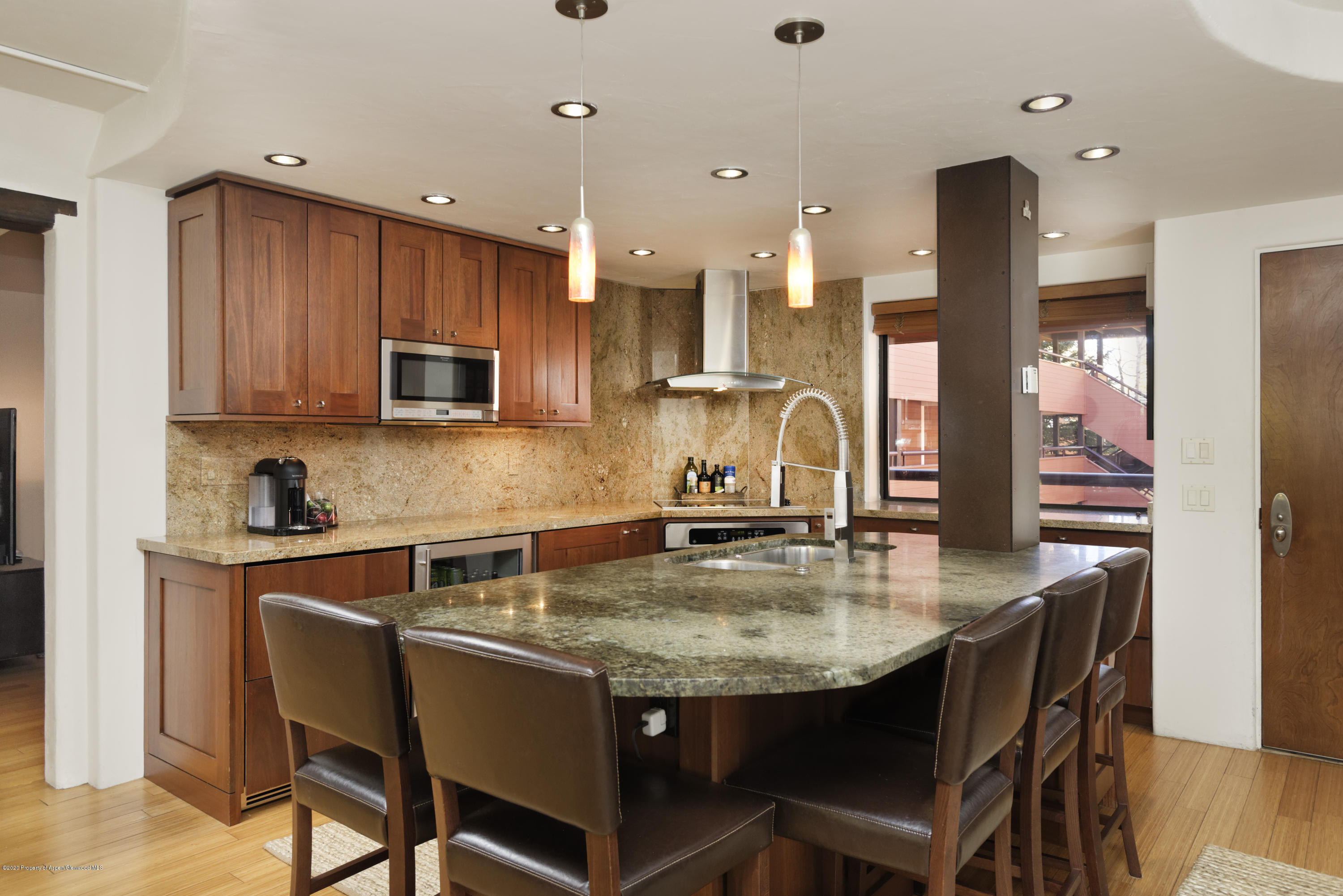 a kitchen with kitchen island granite countertop a table chairs sink and microwave