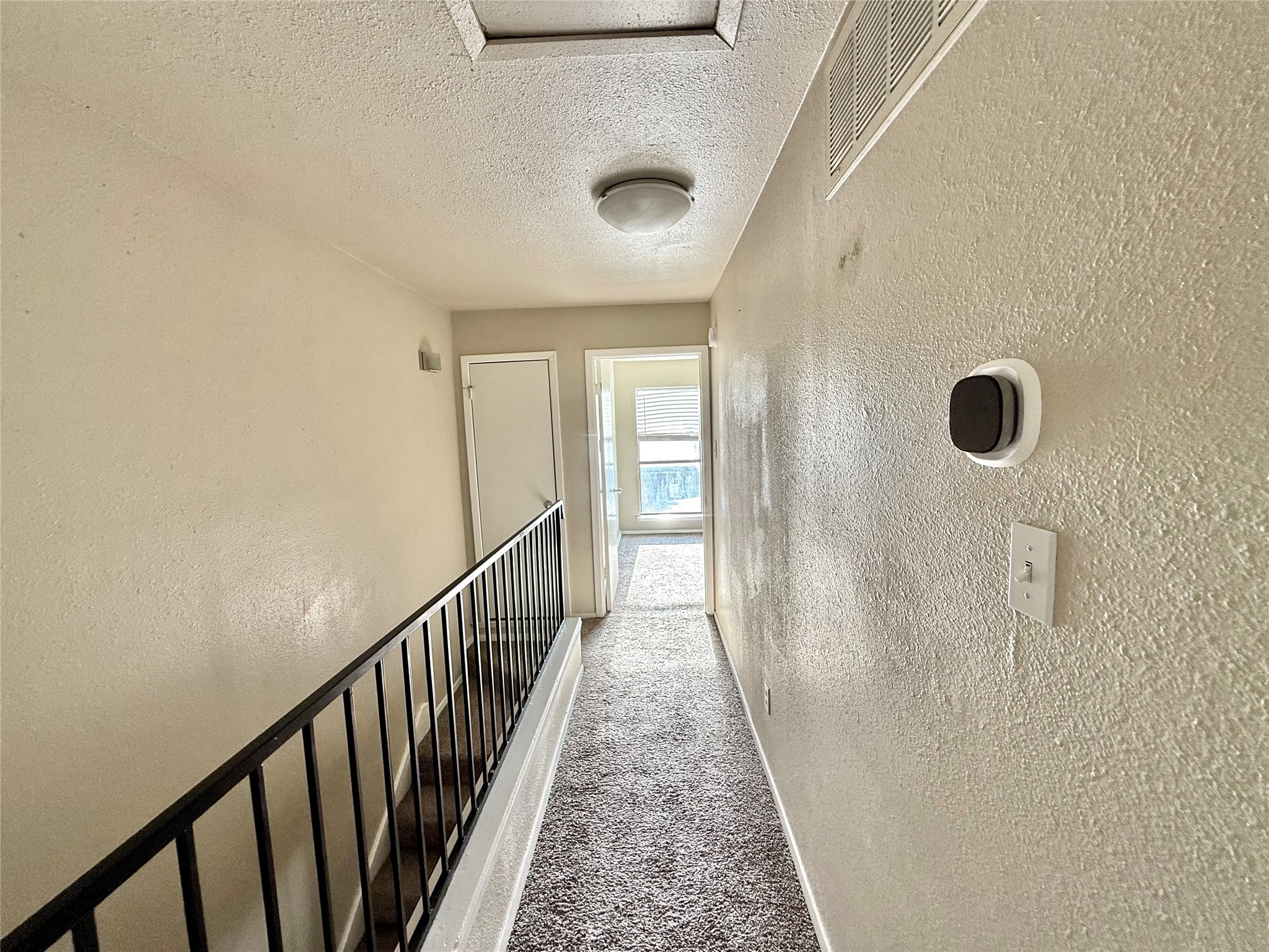 2018 West Rundberg Lane, Unit 6A Austin, TX 78758 - Photo 12 of 17 Hall with a textured wall, carpet flooring, and a textured ceiling