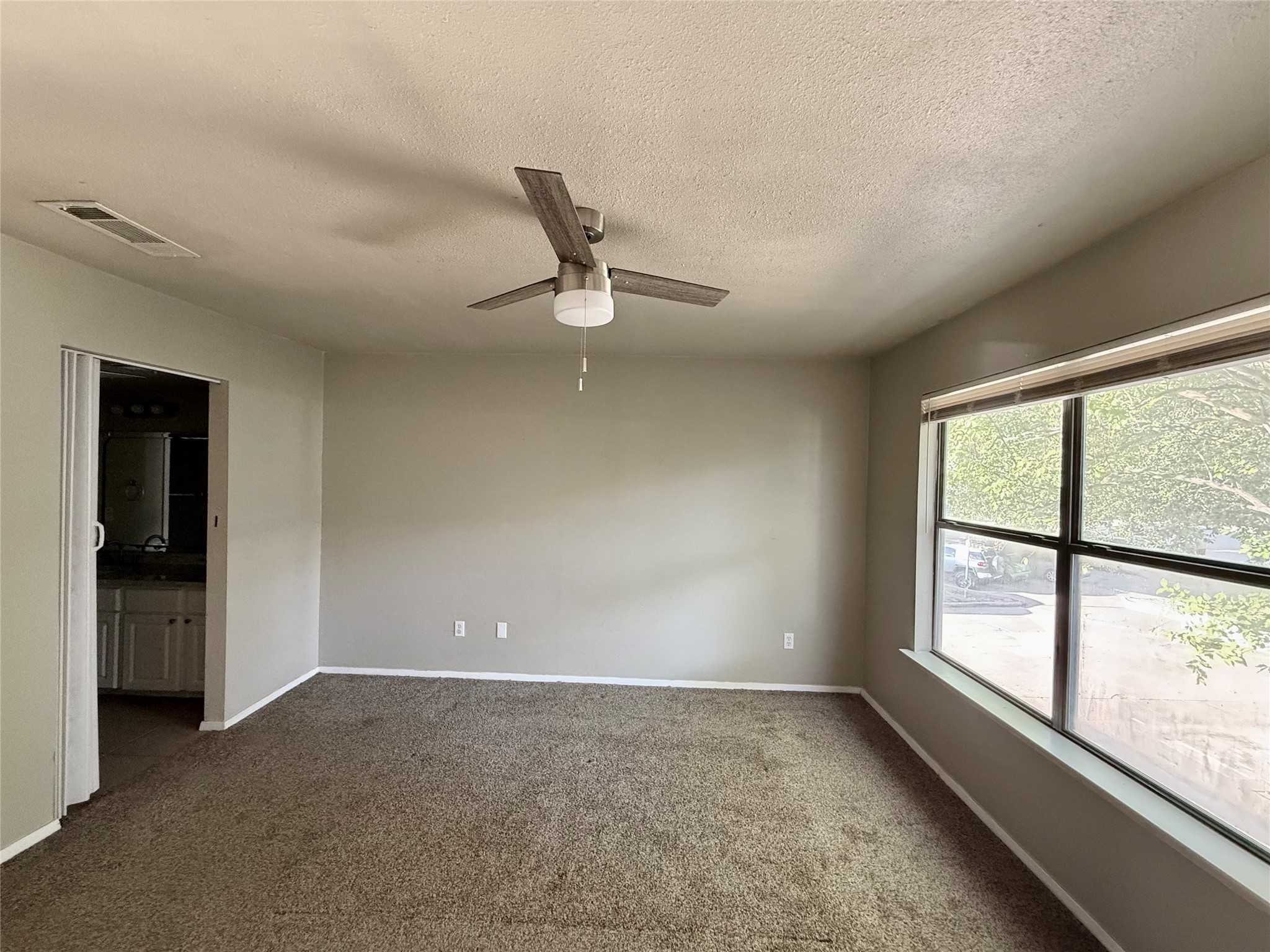 2018 West Rundberg Lane, Unit 6A Austin, TX 78758 - Photo 13 of 17 Spare room featuring dark carpet, a ceiling fan, and a textured ceiling