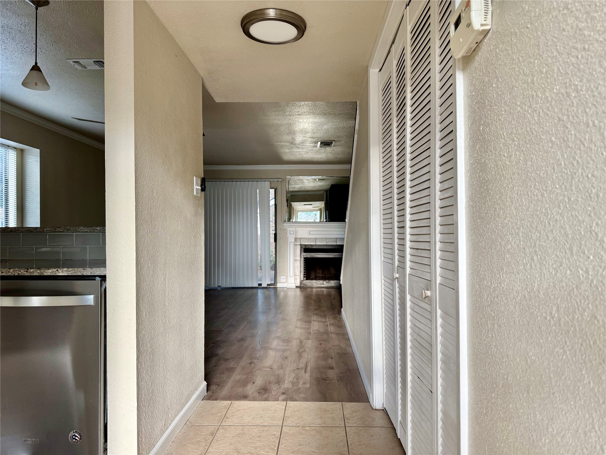 2018 West Rundberg Lane, Unit 6A Austin, TX 78758 - Photo 5 of 17 Corridor featuring a textured wall, crown molding, light tile patterned floors, and a textured ceiling