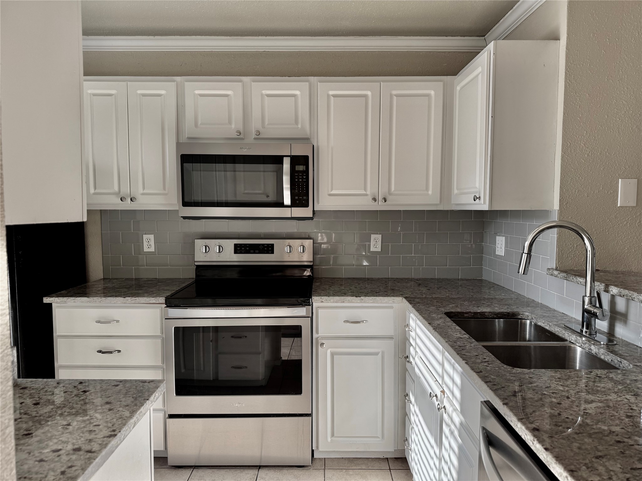 2018 West Rundberg Lane, Unit 6A Austin, TX 78758 - Photo 6 of 17 Kitchen with stainless steel appliances, white cabinets, a textured wall, and ornamental molding