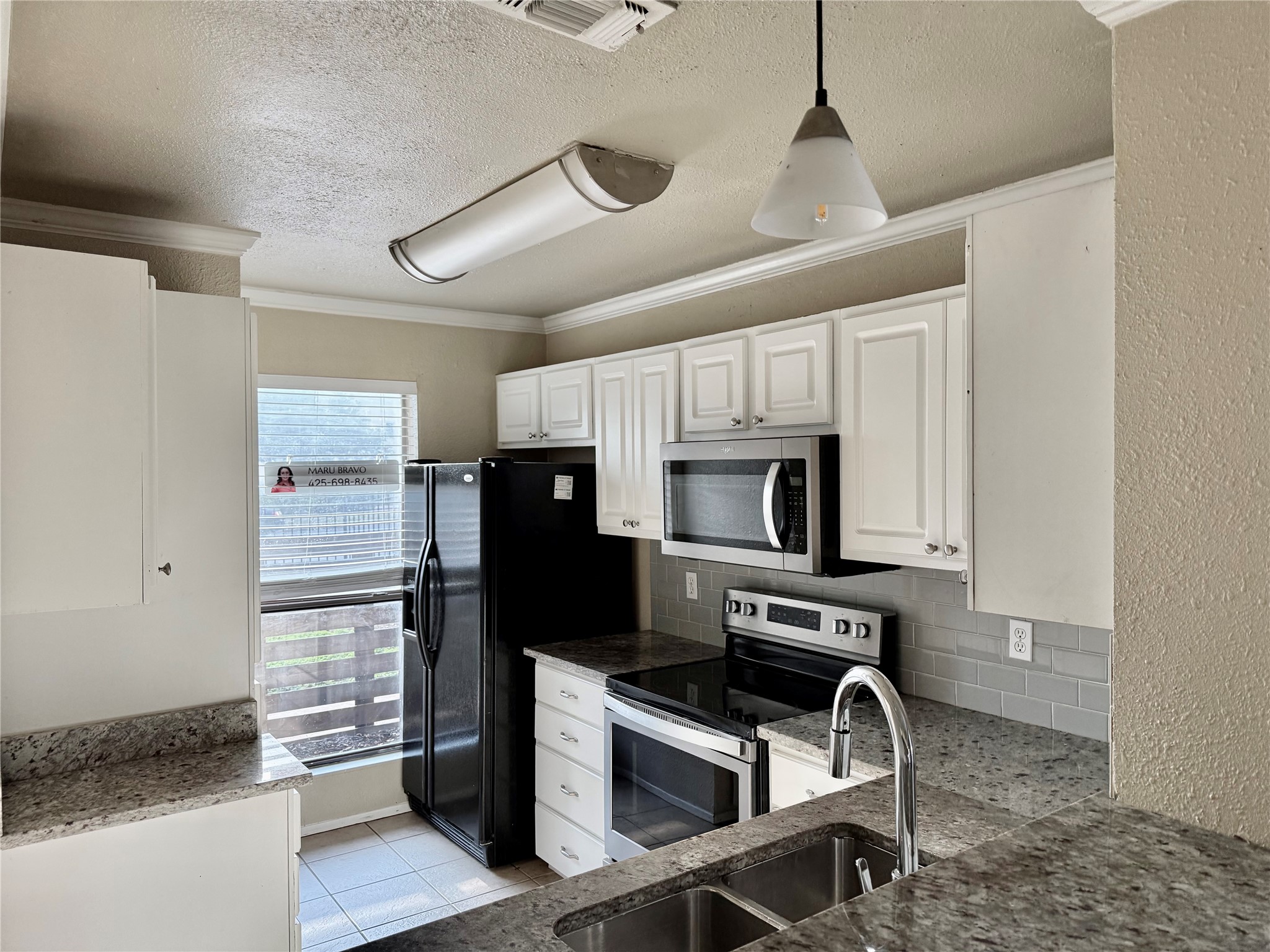 2018 West Rundberg Lane, Unit 6A Austin, TX 78758 - Photo 8 of 17 Kitchen with white cabinets, stainless steel appliances, a textured ceiling, backsplash, and dark stone counters