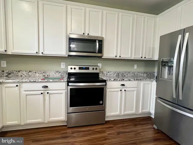 a kitchen with granite countertop a sink and a white cabinets