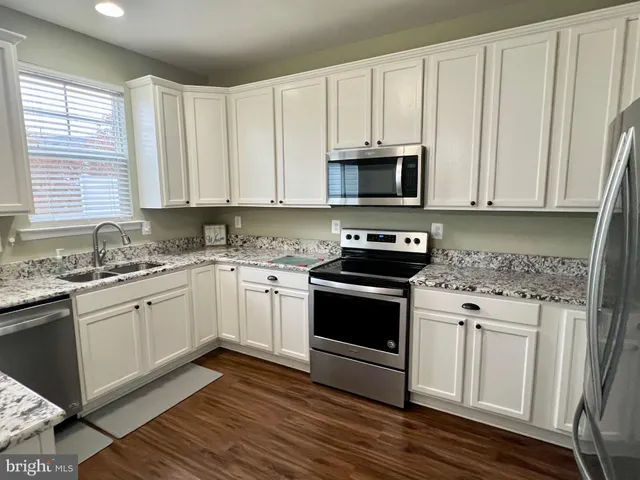 a kitchen with granite countertop white cabinets and white appliances