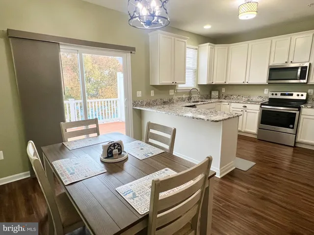 a kitchen with stainless steel appliances granite countertop a stove a sink dishwasher a dining table and chairs with wooden floor