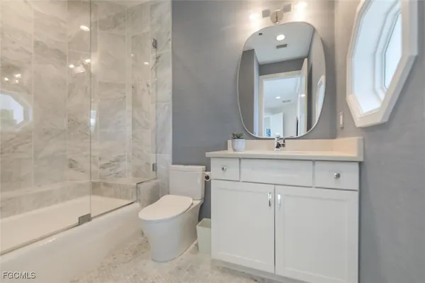 a bathroom with a bathtub shower sink vanity and toilet