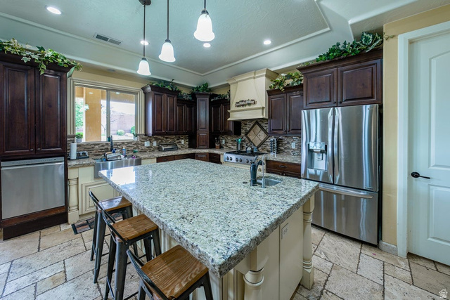 3683 South 2640 West St. George, UT 84790 - Photo 13 of 41 Kitchen featuring a large island with stone countertop, dark wood cabinetry, stainless steel appliances, decorative tiled backsplash, and recessed and pendant lighting
