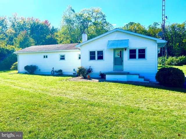 a front view of house with yard and trees in the background