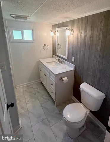 a bathroom with a granite countertop toilet sink and mirror