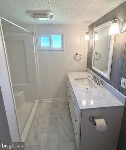 a bathroom with a granite countertop sink a mirror and shower