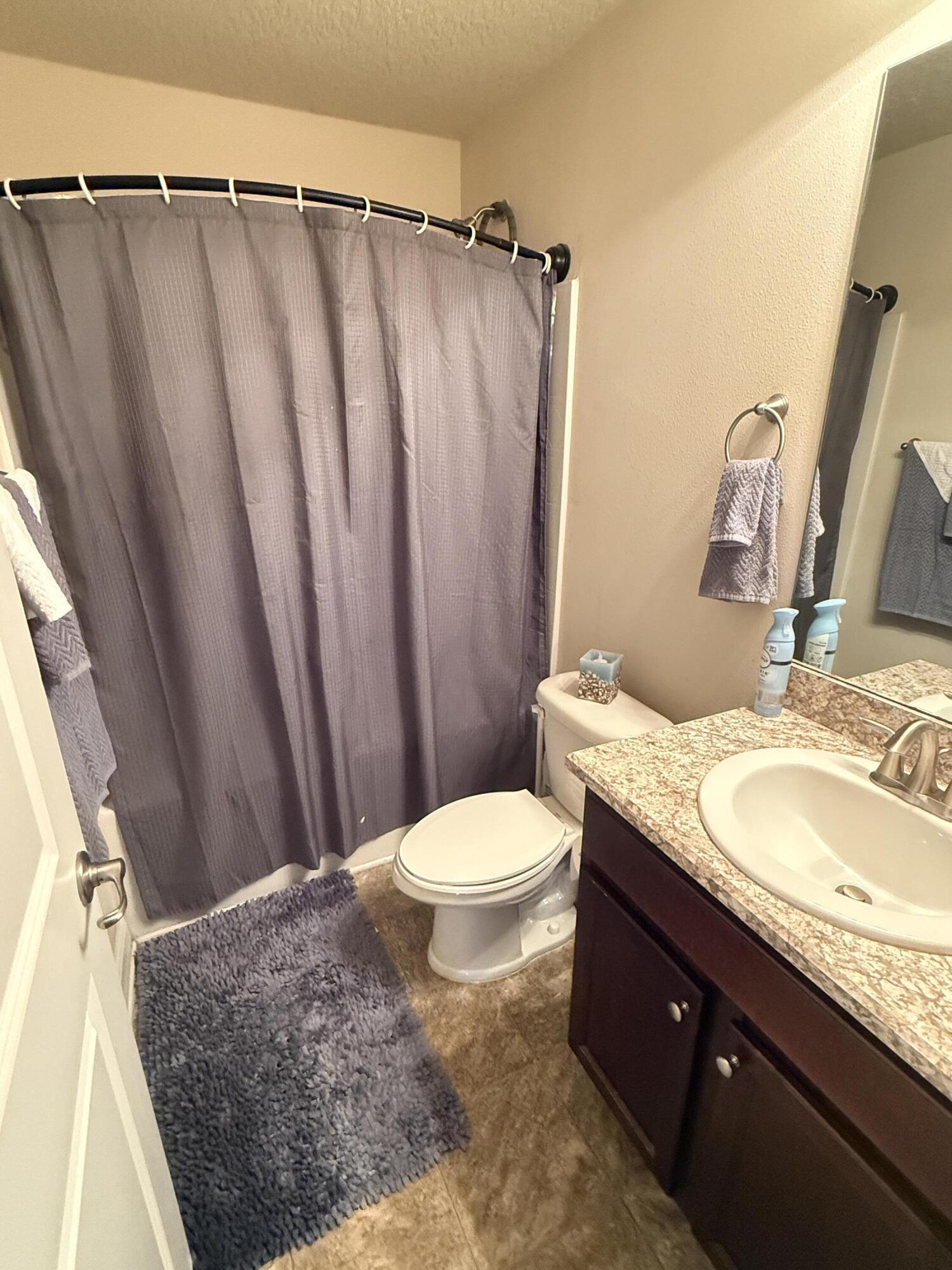 2177 Southeast Dolphin Road Port St. Lucie, FL 34952 - Photo 14 of 16 a bathroom with a granite countertop bathtub sink vanity mirror and toilet