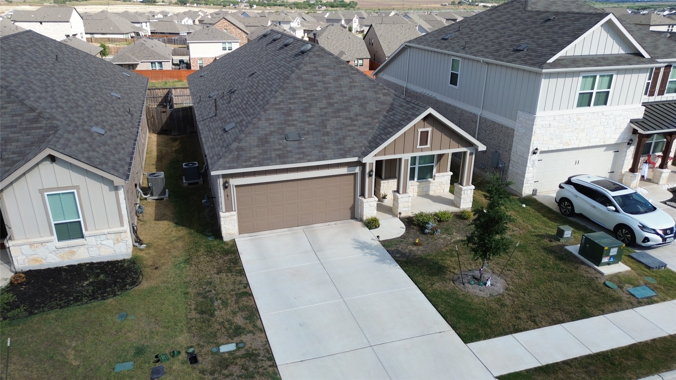 181 Tree Nut Loop Buda, TX 78610 - Photo 29 of 33 A spacious concrete driveway leads to the integrated two-car garage of this modern home.