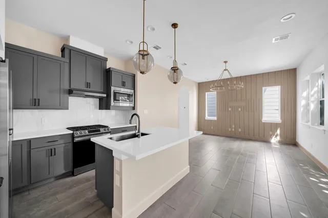 a kitchen with stainless steel appliances granite countertop a sink a stove and a refrigerator