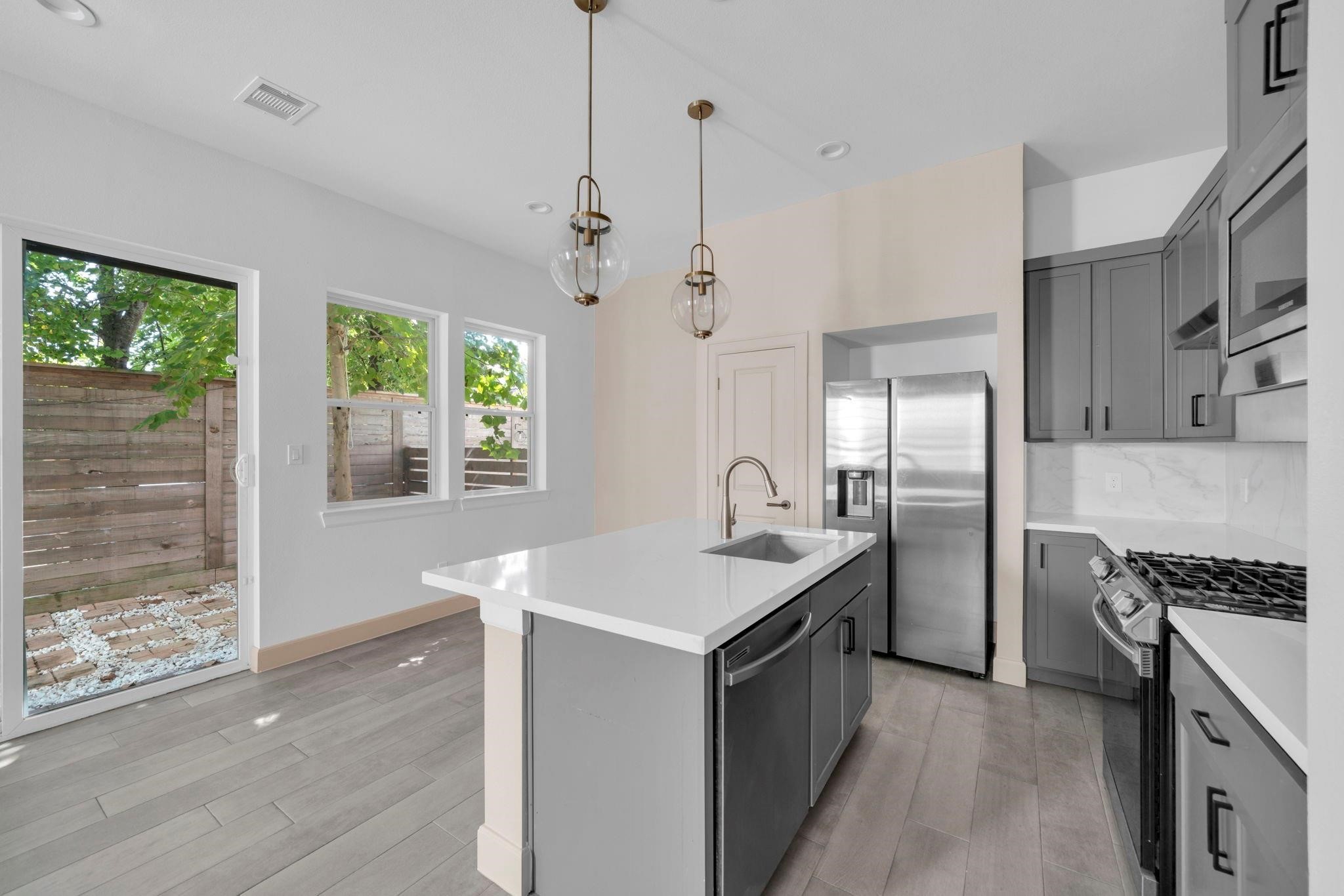 9551 Neuens Road, Unit B Houston, TX 77080 - Photo 9 of 32 a kitchen with stainless steel appliances granite countertop a refrigerator a sink dishwasher a stove and a dining table with wooden floor