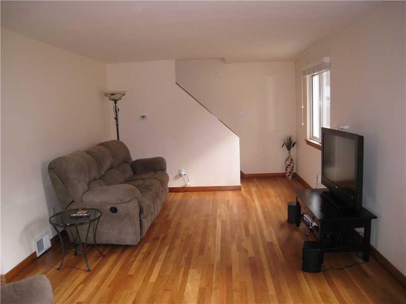 1507 Homestead Road Penn Hills, PA 15147 - Photo 4 of 17 Living Room. The front door opens into the living room, featuring refinished hardwood floors and neutrally tones walls with natural wood baseboard trim.