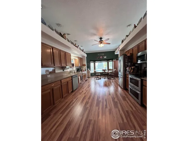 a kitchen with stainless steel appliances granite countertop a stove a refrigerator a sink dishwasher and a oven with wooden floor