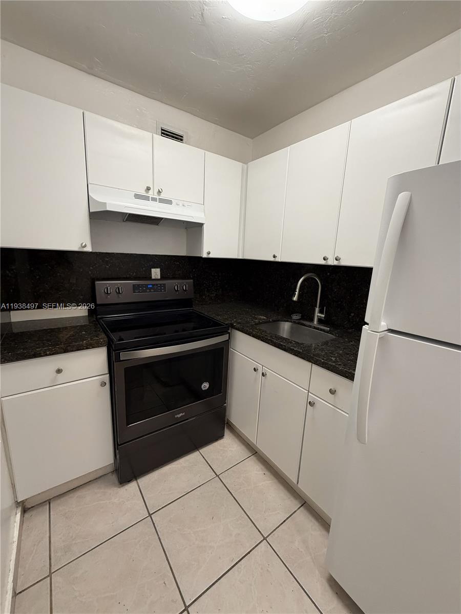 1860 Southwest 22nd Street, Unit 7 Miami, FL 33145 - Photo 2 of 8 a kitchen with granite countertop white cabinets and black appliances