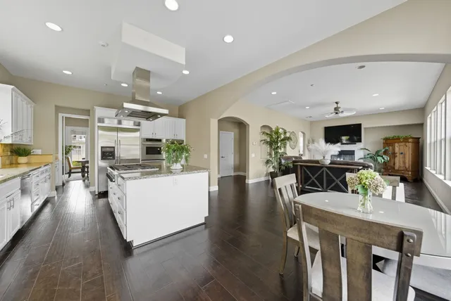 a living room with stainless steel appliances furniture a rug kitchen view and a faucet